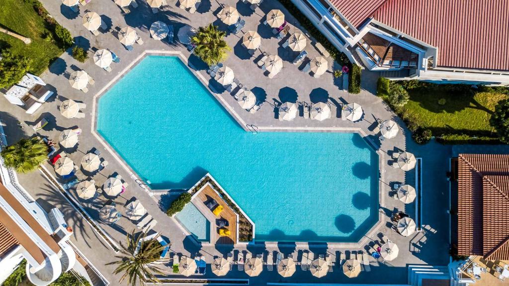 Hotel Niriides Beach في كوليمبيا: اطلالة علوية على مسبح به طاولات وكراسي