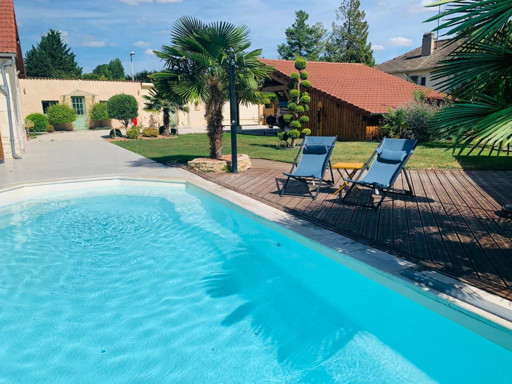 a swimming pool with two chairs and a house at Les chambres du Bonheur in Fontaine-sous-Jouy
