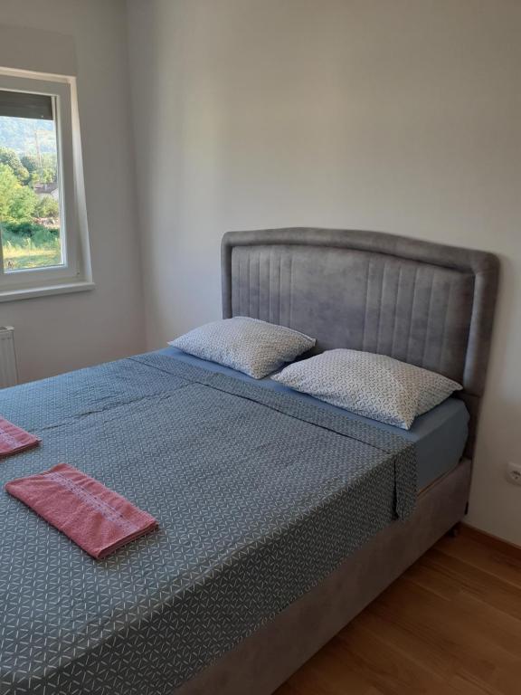 a bed with a blue comforter and a window at Apartman kod Brke 20 A Bulevar Vojvode Živojina Mišiča in Banja Luka
