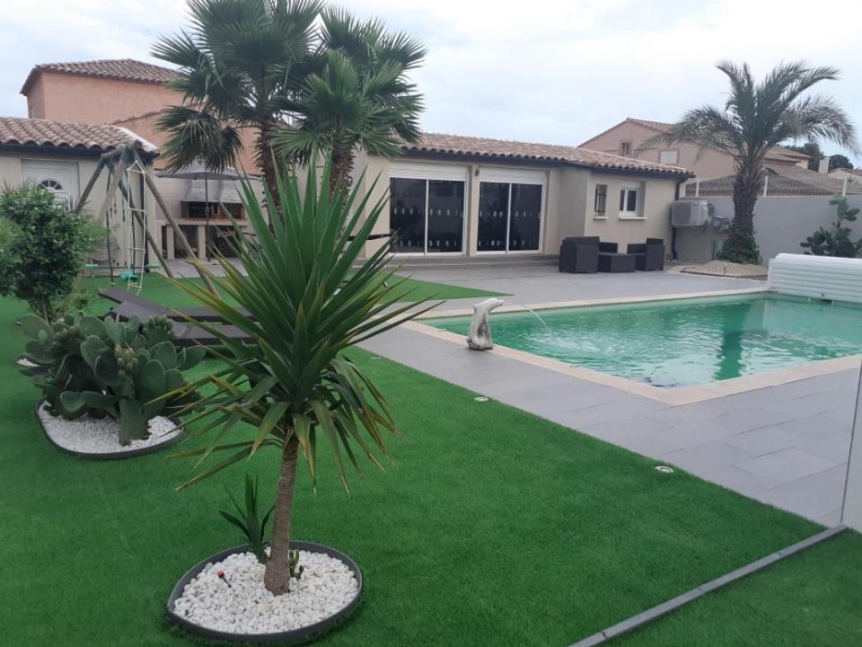 un palmier dans une cour avec une piscine dans l'établissement Villa Piscine, à Montady