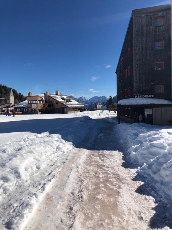 une route recouverte de neige à côté d'un bâtiment dans l'établissement Paradise Dolomiti flat, à Falcade
