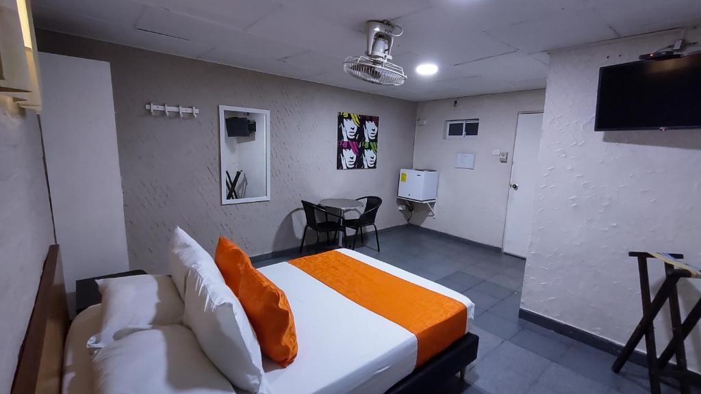 um quarto com uma cama, uma televisão e um sofá em Casa Boston Inn em Barranquilla