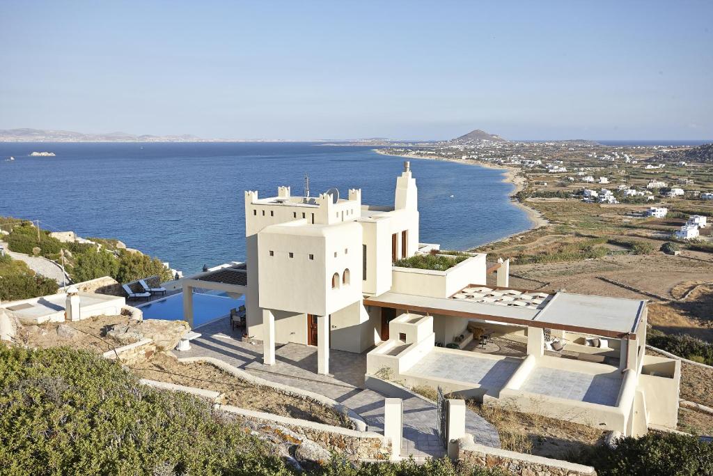 a white building on top of a hill next to the ocean at Tower Resort Naxos Island in Plaka