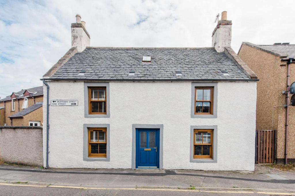 una casa blanca con una puerta azul en una calle en King Street Cottage in the centre of Inverness, en Inverness