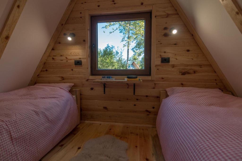 two beds in a room with a window at Log cabins Banjska stena in Mitrovac