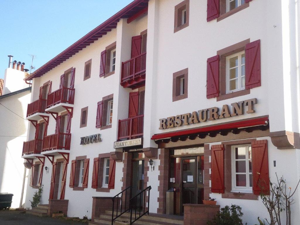 un bâtiment avec des fenêtres à volets rouges et un appartement areskun dans l'établissement Hôtel Juantorena, à Saint-Étienne-de-Baïgorry