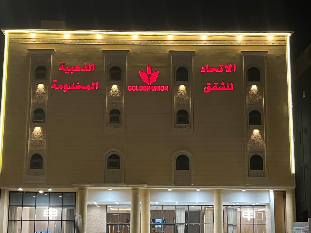 a building with neon signs on the side of it at الاتحاد الذهبية للشقق المخدومة 2 in Al Ahsa