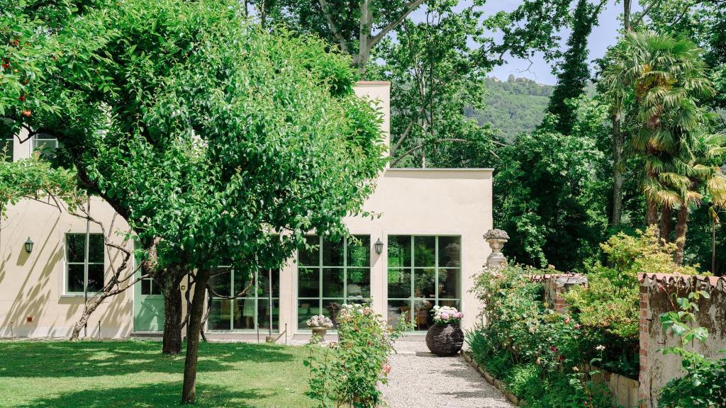 una casa con un jardín y un árbol en The Greenhouse Luxury Villa on Lake Como en Como