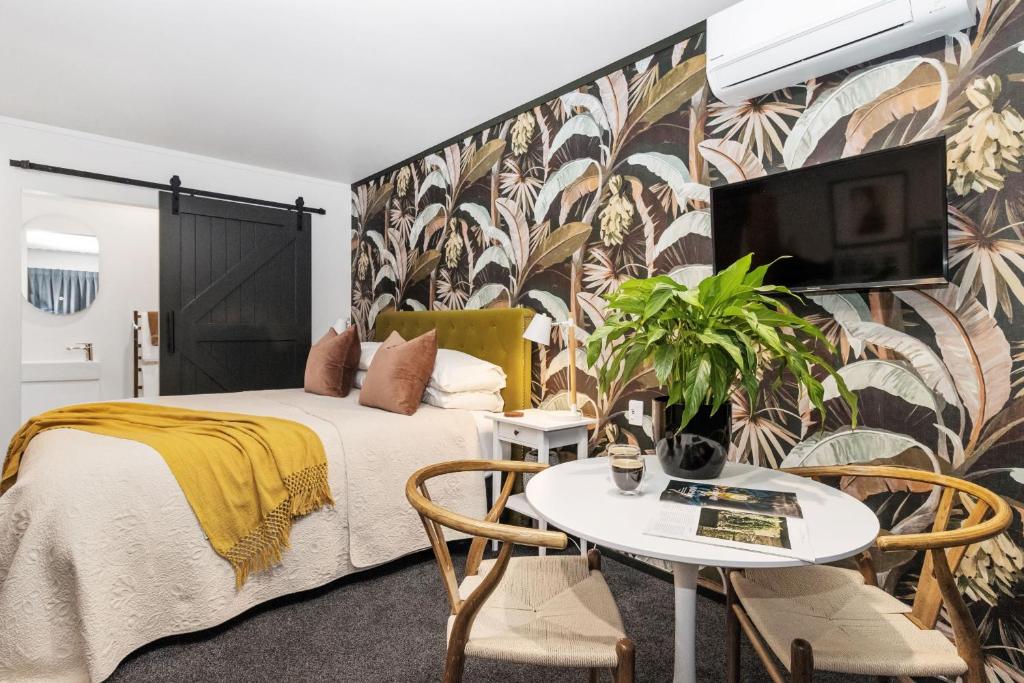 a bedroom with a bed and a table with a tv at Matamata Lodge in Matamata