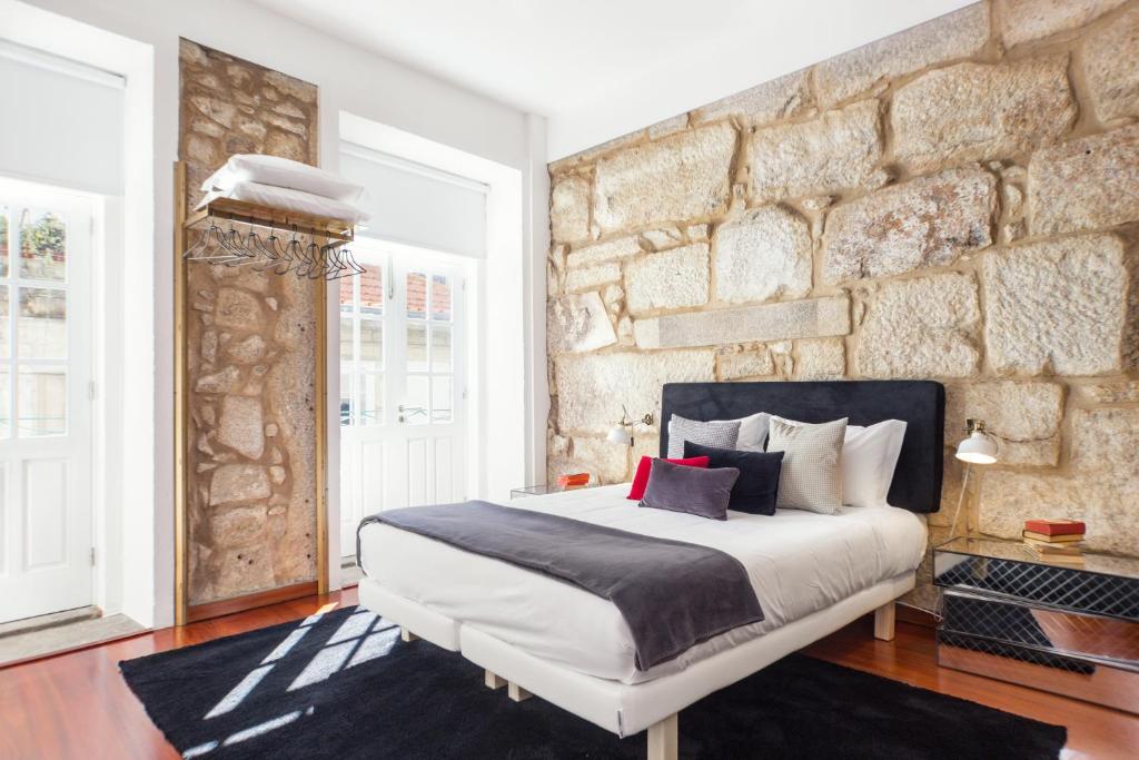 a bedroom with a large bed and a stone wall at Oporto Chic & Cozy Studio Apartments in Porto