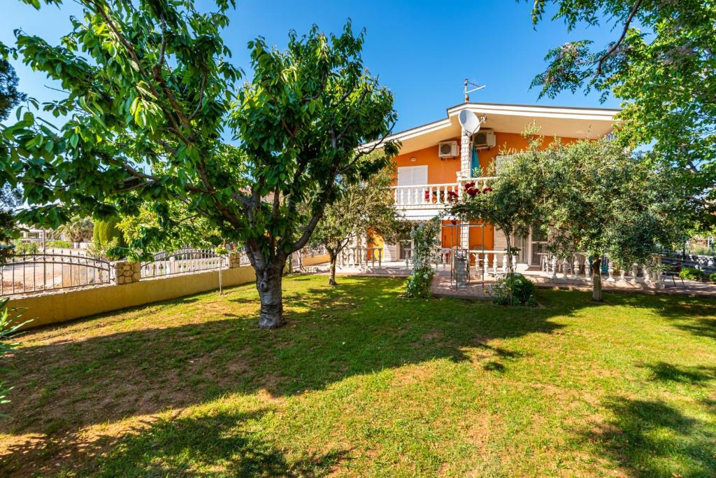 ein orangefarbenes Haus mit einem Baum im Hof in der Unterkunft Apartments by the sea Privlaka, Zadar - 18652 in Privlaka