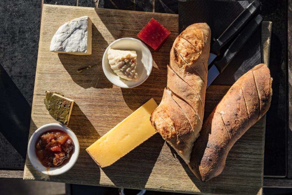 a wooden cutting board with bread and cheese and other foods at Bruny Island Oceanfront Luxe Cabin with Spa in Adventure Bay