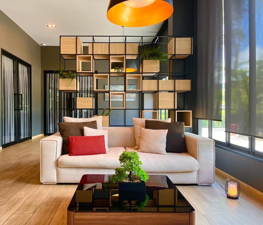 チャンタブリーにあるbliQ Hotel Chanthaburiのリビングルーム(赤い枕と白いソファ付)