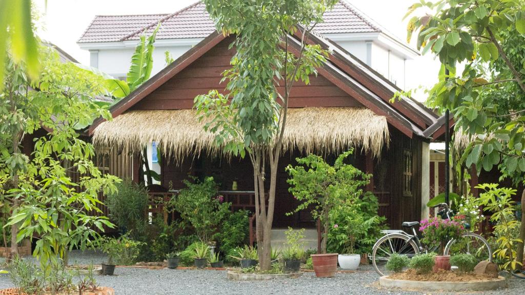a house with a straw roof with a bicycle in front at Treuy Koh Bungalow in Kampot