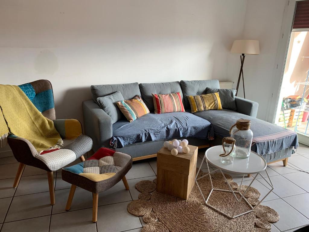 sala de estar con sofá azul y sillas en Le tout à pied!, en Ciboure