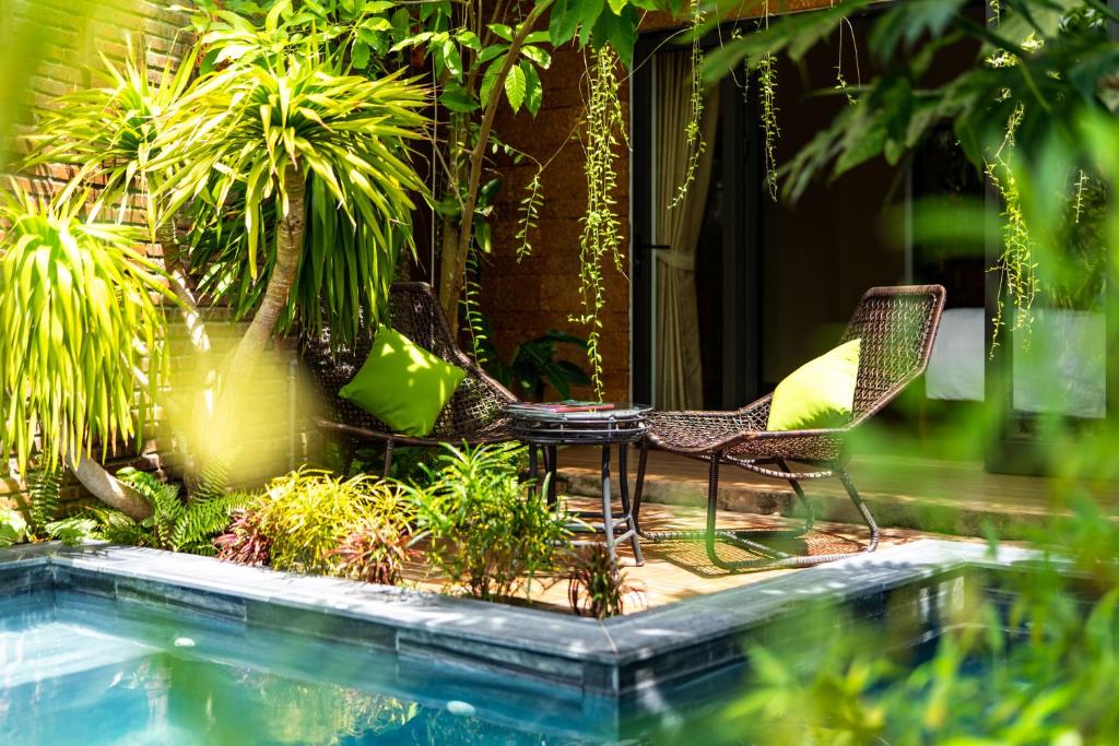 een patio met 2 stoelen en een tafel naast een zwembad bij Olala An Bang Villa in An Bàn (2)