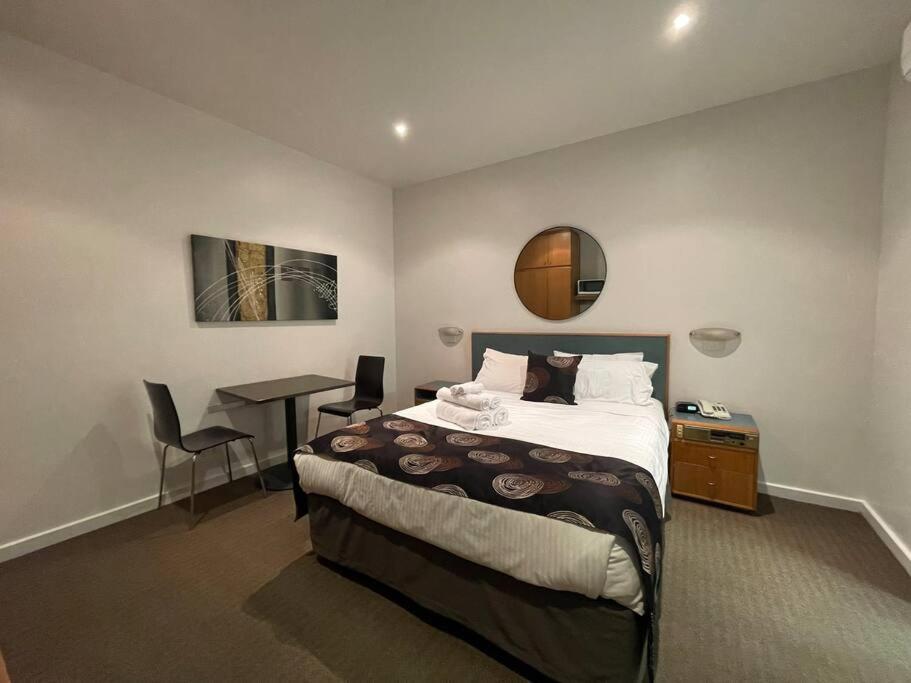 een slaapkamer met een bed, een bureau en een tafel bij 408 Lovely one BR ex hotel ensuite room in city in Adelaide