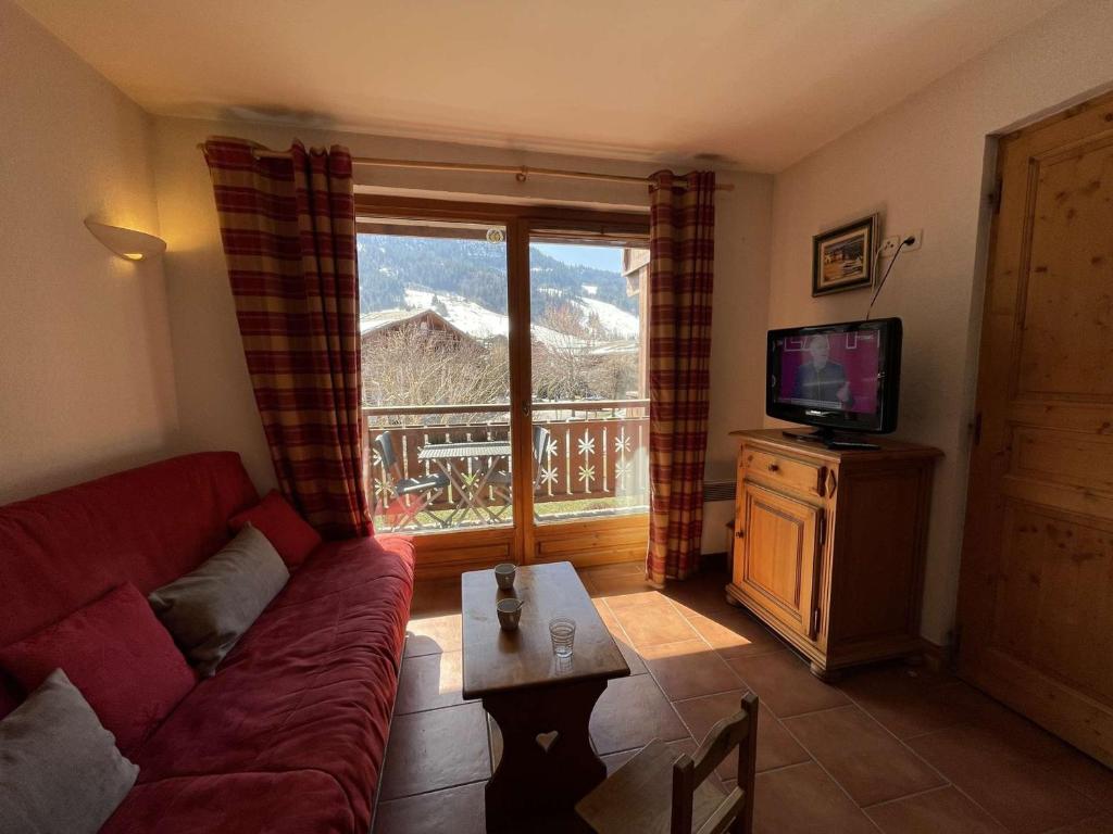 salon z kanapą, telewizorem i oknem w obiekcie Appartement cosy avec piscine à 300m du lac de baignade, proche du village et des pistes - Praz-sur-Arly - FR-1-603-62 w mieście Praz-sur-Arly