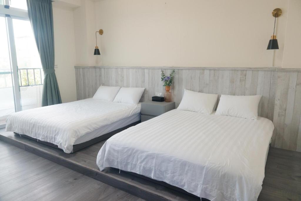 台東市的住宿－宿嘻民宿，卧室内的两张床,配有白色床单