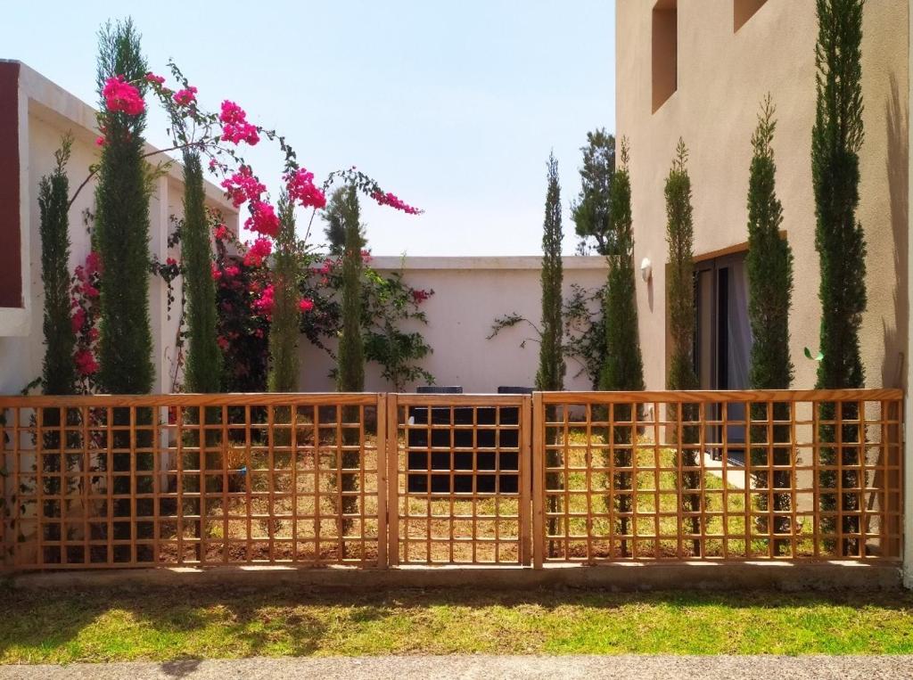 um cachorro atrás de um portão em frente a uma casa em Taghazout bay - Tawenza Medina - Apt avec piscine partagée et Jardin em Tamraght Ouzdar