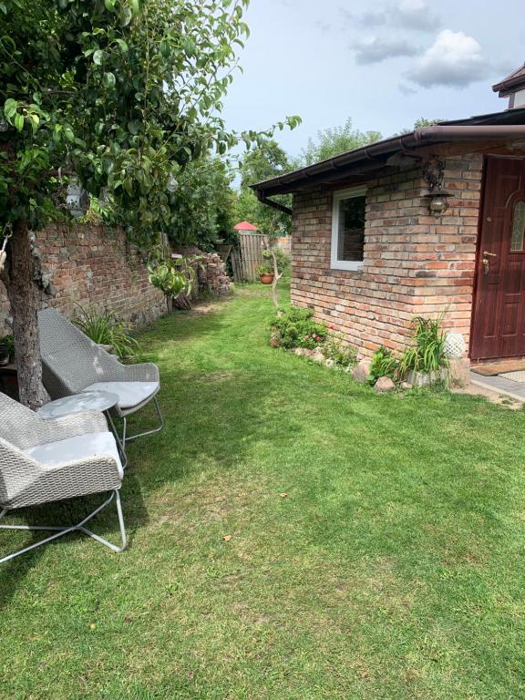 a yard with two chairs and a brick building at Uroczy Domek in Złocieniec