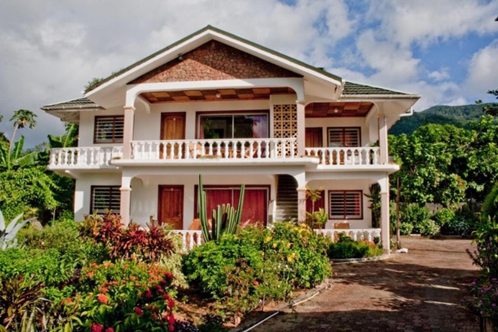 a white house with a balcony and some bushes at Villa de Roses in Beau Vallon
