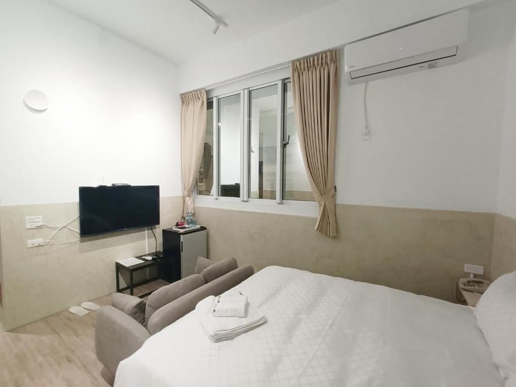 1 dormitorio con cama, sofá y TV en No 9 Hotel-九號文旅 en Tainan