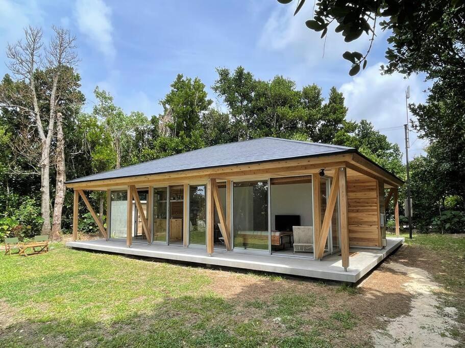 eine große Holzhütte mit Glastüren auf einem Feld in der Unterkunft 久米島 SHINMINKA Villa in Kumejima