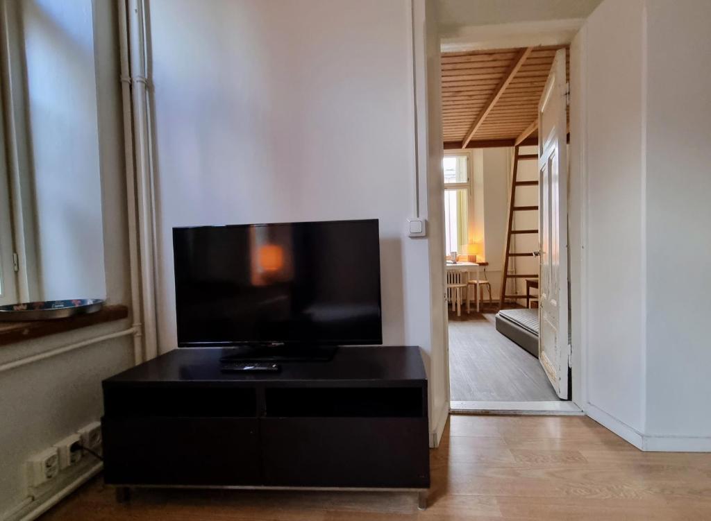 a living room with a television on a black dresser at 4 Blocks From Stockmann in Helsinki
