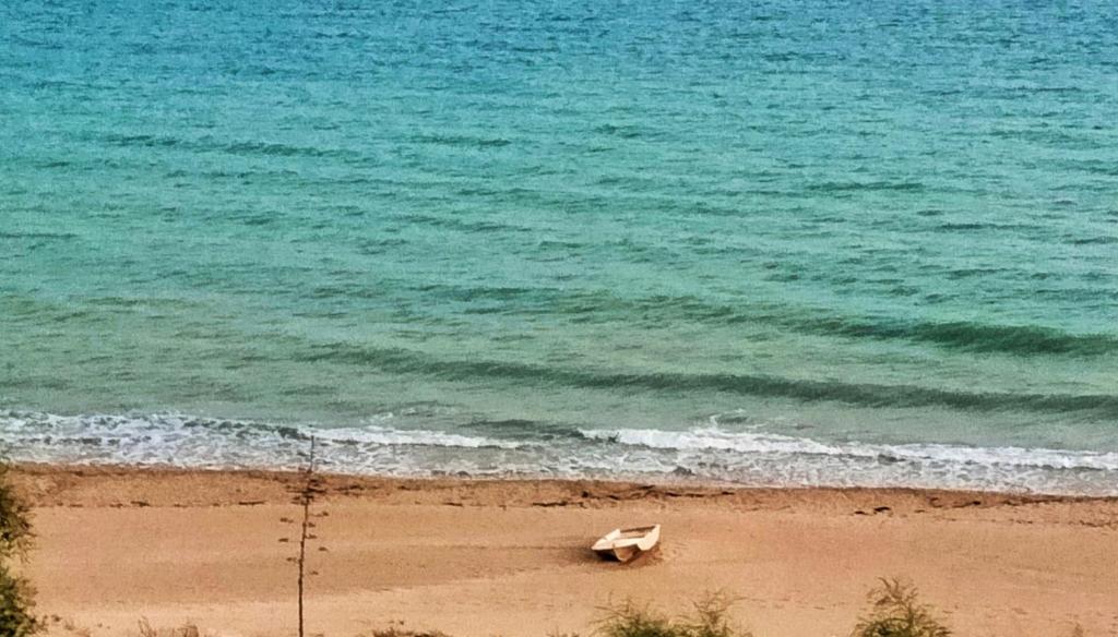 a boat laying on the beach next to the ocean at natura e relax sul mare in Gela