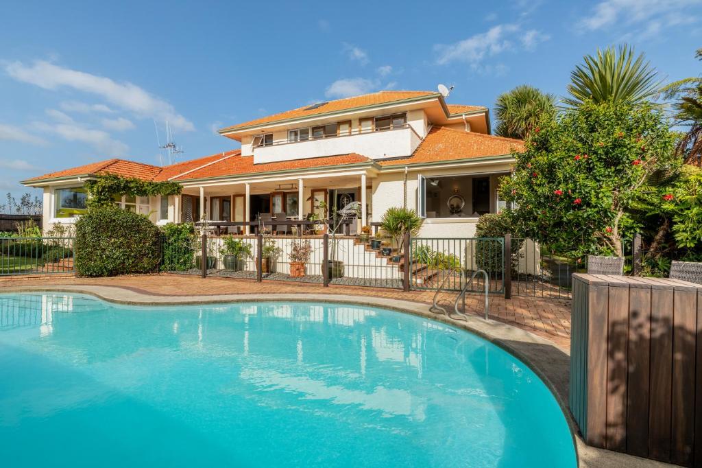 a house with a swimming pool in front of a house at Grange Harbour View B&B in Tauranga