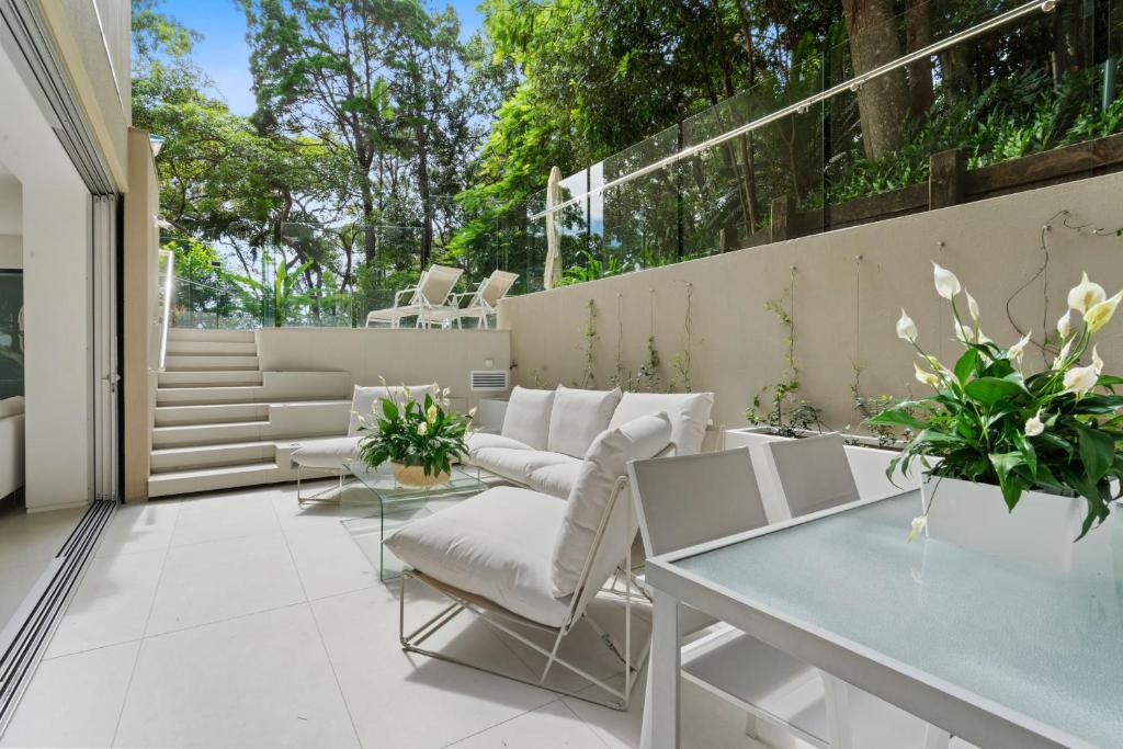 a patio with white furniture and a glass table at Little Cove Court - Apt 8 in Noosa Heads