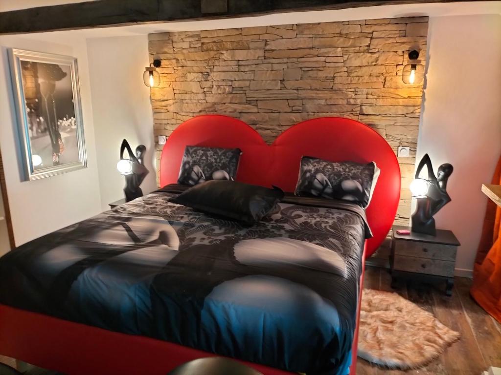 - un lit rouge dans une chambre dotée d'un mur en briques dans l'établissement L'idyle loft érotique détente, à Callac