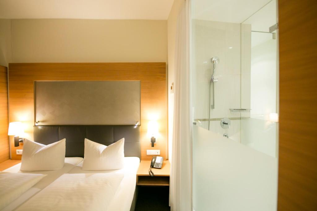 a bedroom with a bed with a phone and a shower at Hotel Sailer in Innsbruck