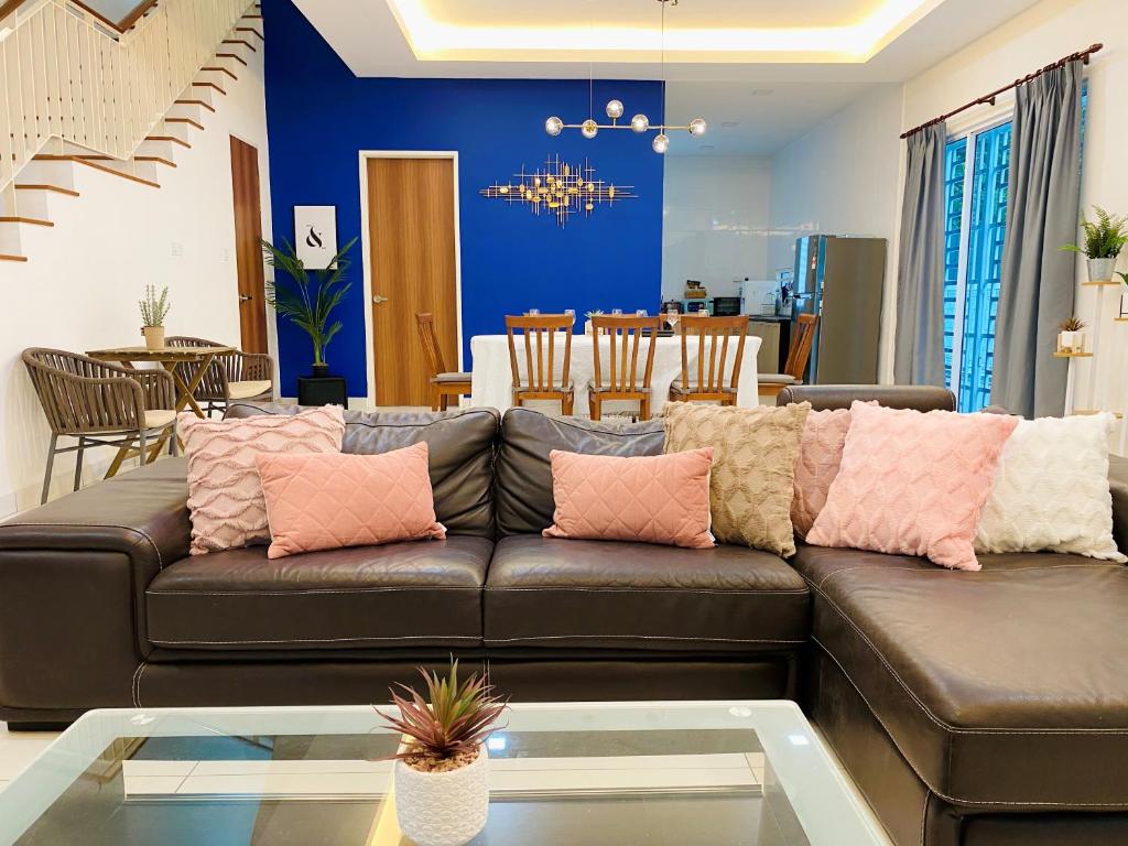 sala de estar con sofá marrón con almohadas rosas en 5Bedroom Villa @ Seremban 20pax Netflix Projector Pool, en Seremban