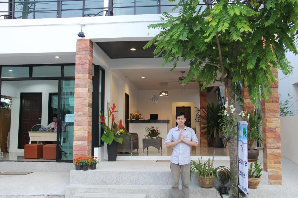 Ein Mann steht vor einem Haus. in der Unterkunft The Seashore Kamala Service Apartment in Kamala Beach