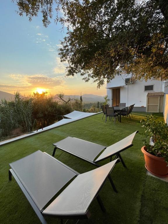 un patio trasero con mesas y sillas en el césped en Corfu Gaia View Studio en Episkopianá