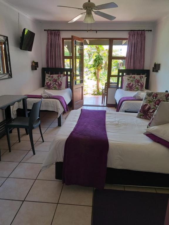 um quarto com 3 camas e uma mesa e cadeiras em African Sun Guest House em Molen Drift