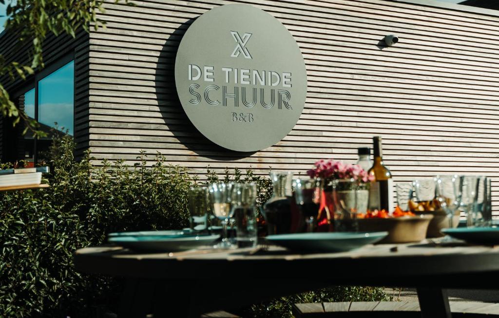 a table with plates and wine glasses in front of a building at B&B De Tiendeschuur in Evergem