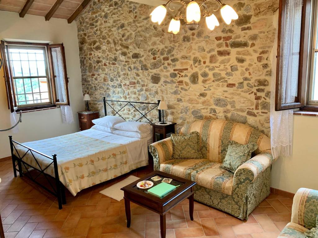 a bedroom with a bed and a couch and a chair at Casina di Rosa in Civitella Marittima