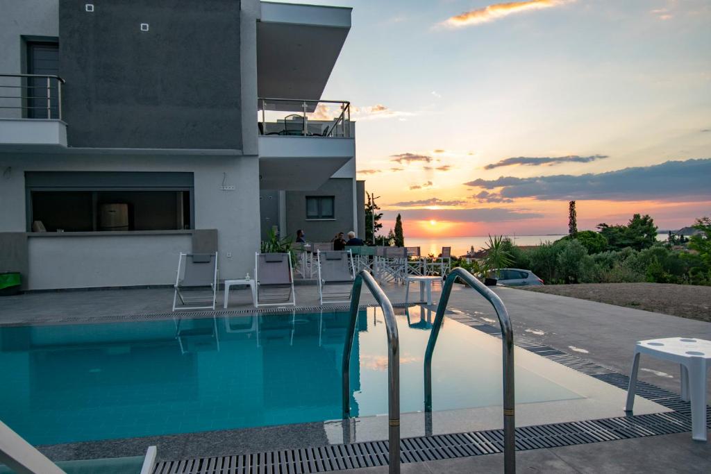 a house with a swimming pool with a sunset in the background at Heraclea Luxury Suites in Nea Iraklia