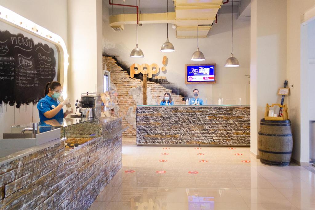 a bar in a restaurant with a woman wearing a mask at POP! Hotel Kelapa Gading in Jakarta