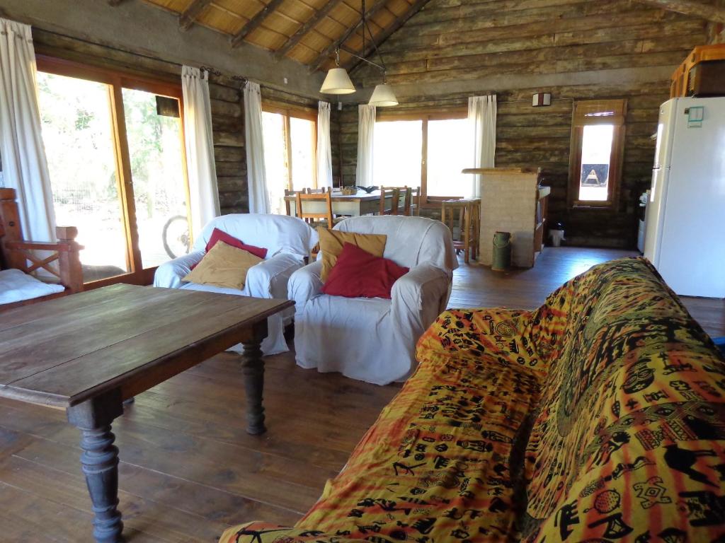 uma sala de estar com duas cadeiras brancas e uma mesa de madeira em Cabaña Navajuá em La Paloma