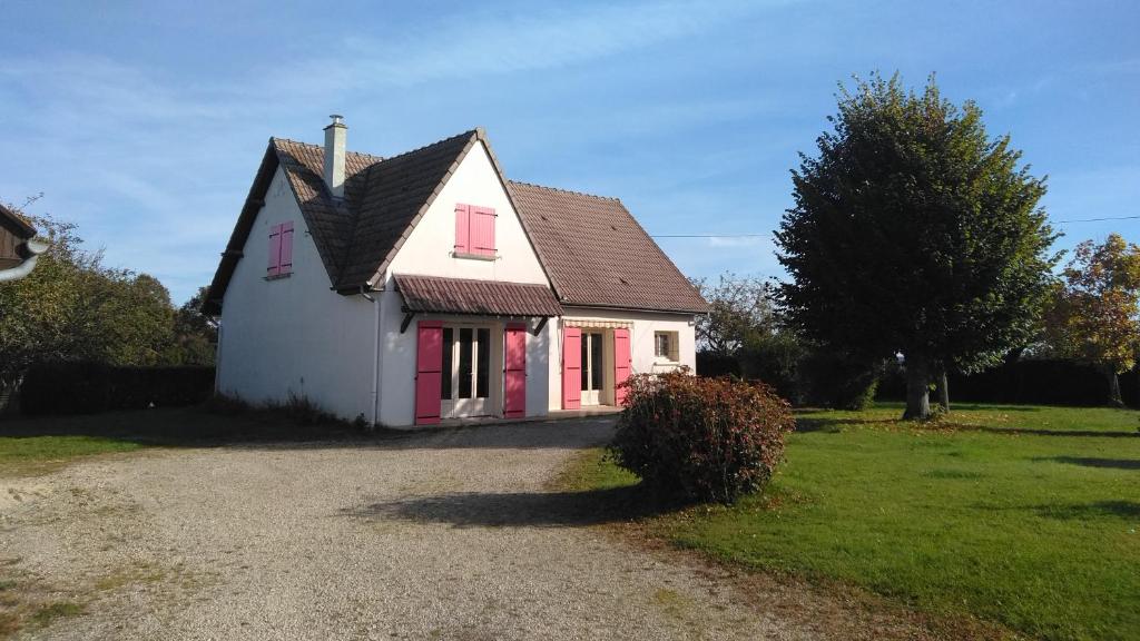 ein kleines weißes Haus mit roten Rollläden auf einem Hof in der Unterkunft Grande Maison de plain pied avec jardin arboré. in Champignelles