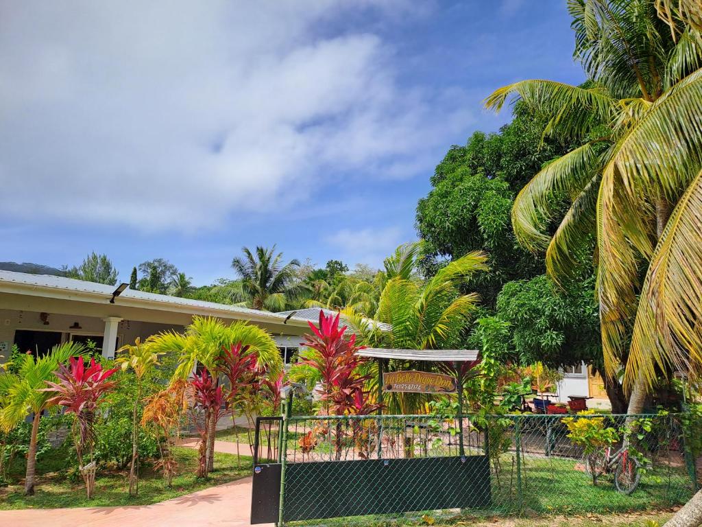 a fence in front of a house with palm trees at La Belle Digue Don in La Digue