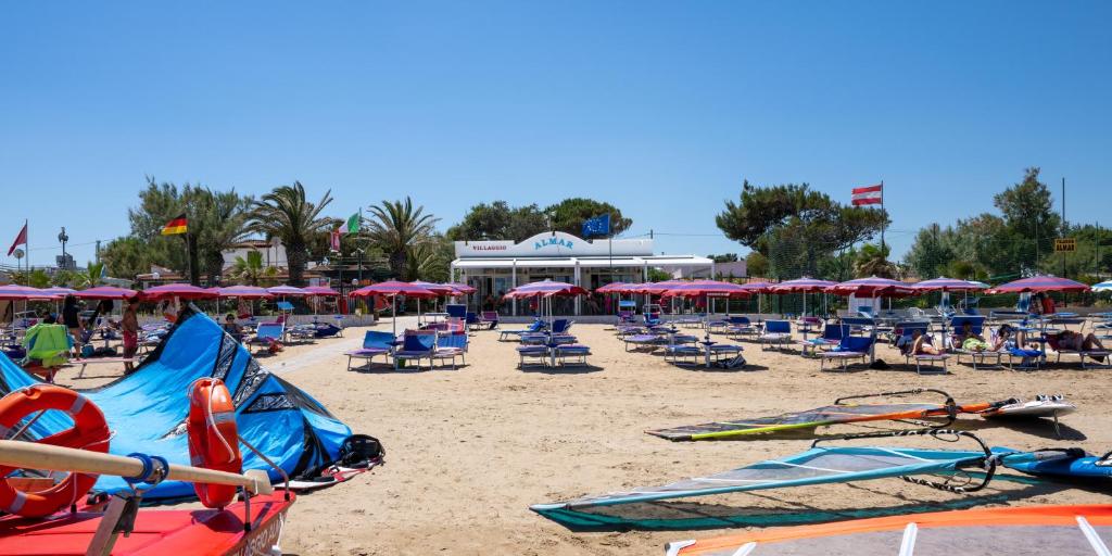 una playa con sillas y sombrillas rojas y espectacular en Villaggio Almar en Vieste