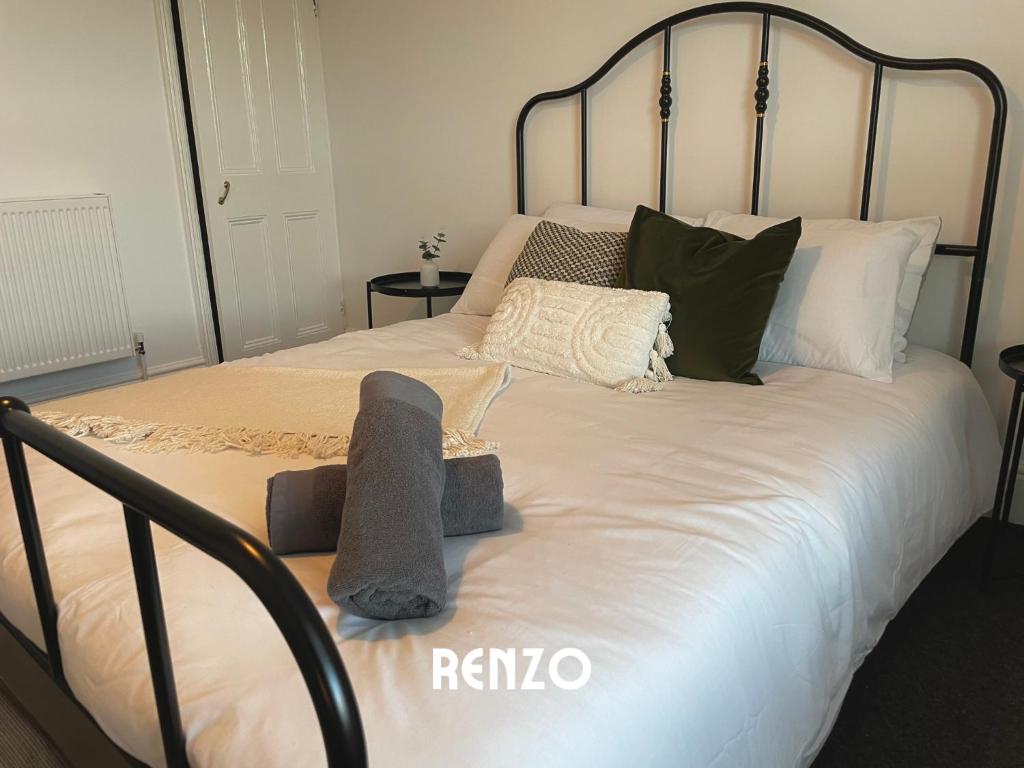 a bed with a black frame and pillows on it at Spacious 2 Bedroom home in Lincoln by Renzo, Victorian Townhouse, Flexible Check-In! in Lincolnshire