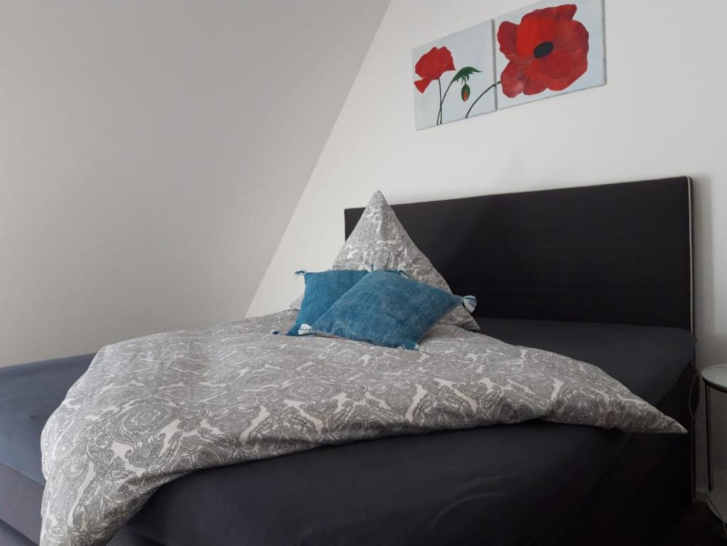 a bed with a gray comforter and a red flower painting at Die Französin - Ingo Telschow & Catherine Tempier Gbr in Deidesheim