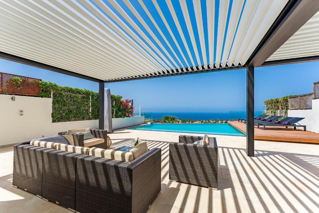 a patio with awning and chairs and a swimming pool at Chalet Golf Costa Adeje 3A003 in Adeje