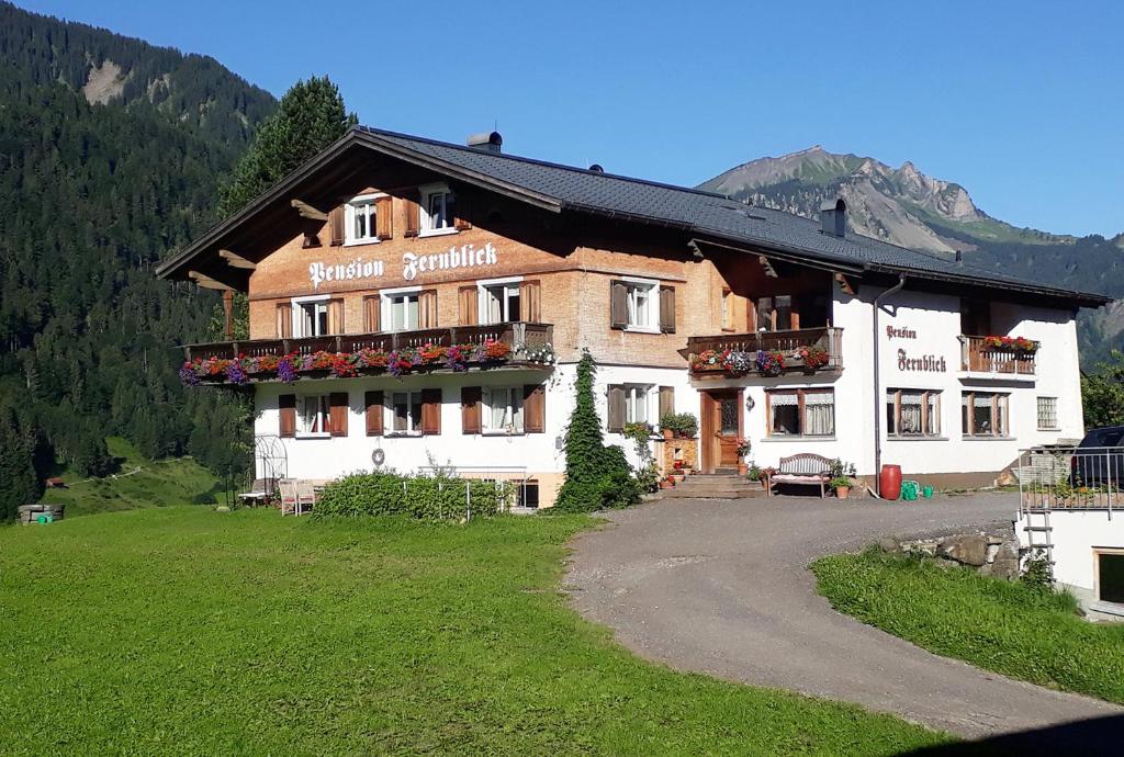 a large building with a balcony with flowers on it at Fernblick Frühstückspension in Schoppernau